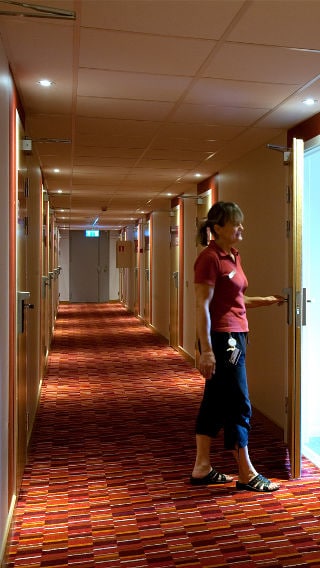 A woman stands in a Spar Hotel corridor, illuminated by Philips hotel lighting